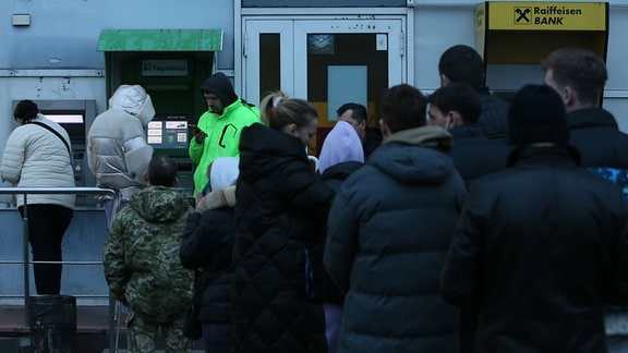 Menschen stehen Schlange vor einer Bank in Kiews, Ukraine