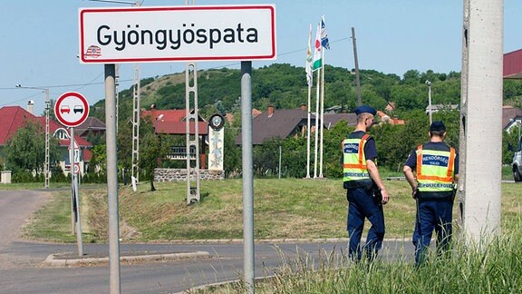 Gyöngyöspata. Ortsschild mit rechtsradikalem Aufkleber und Polizei. Der Ort war zuvor unter Druck verschiedener rechtsradikaler Milizen geraten.