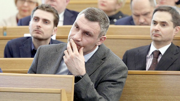 Vitali Klitschko hört mit anderen Menschen einem Vortrag zu.