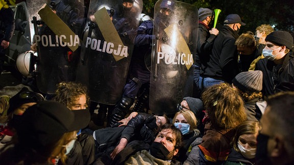 Demonstranten liegen vor Polizisten auf dem Straßenpflaster