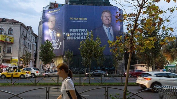 Straßenszene - Fußgänger laufen an einem Wahlplakat in Bukarest vorbei, das Klaus Iohannis zeigt
