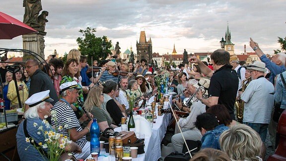 Menschen feiern in Prag auf der Karlsbrücke mit einem Abendessen an einer 500meter langen Tafel.