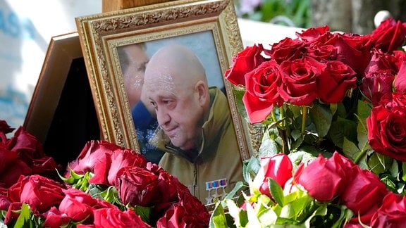 Ein Porträt von Jewgeni Prigoschin neben roten Rosen