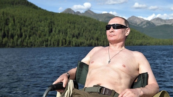 Vladimir Putin relaxt mit freiem Oberkörper am See.