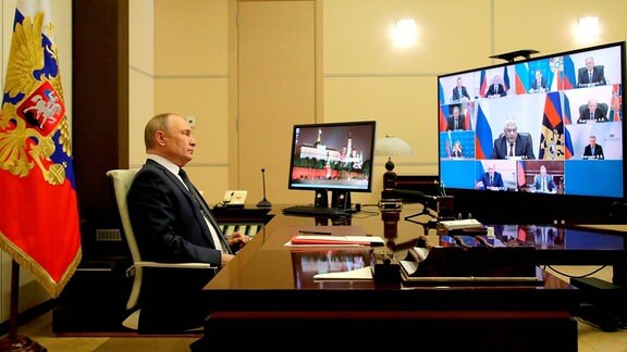Vladimir Putin am Schreibtisch vor mehreren Monitoren