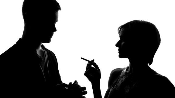 Ein Mann zündet einer Frau eine Zigarette an