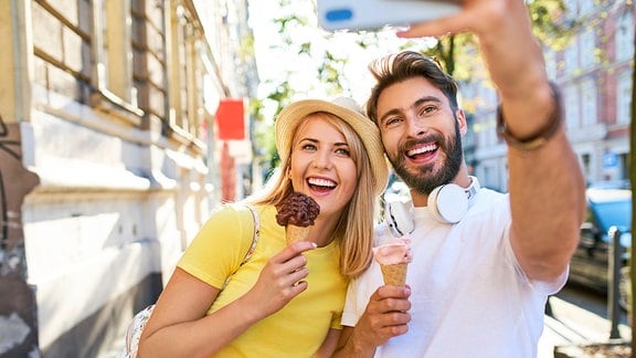 Glückliches Paar nimmt ein Selfie auf, während es Eis isst.