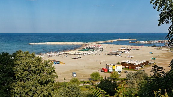 Modern Beach in der Hafenstadt von Constanta, am Horizont eine Warteschlange von Schiffen, die darauf warten, im Hafen abgefertigt zu werden.