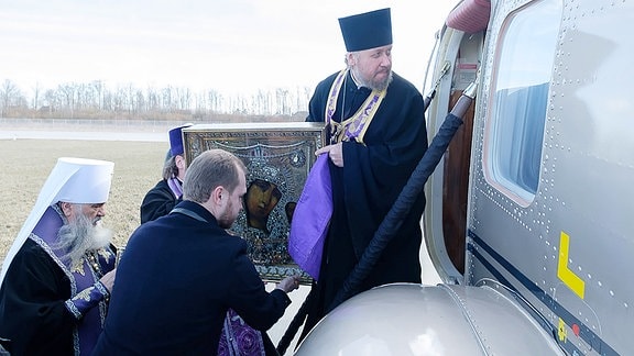 Geistliche besteigen einen Hubschrauber mit einer Ikone.