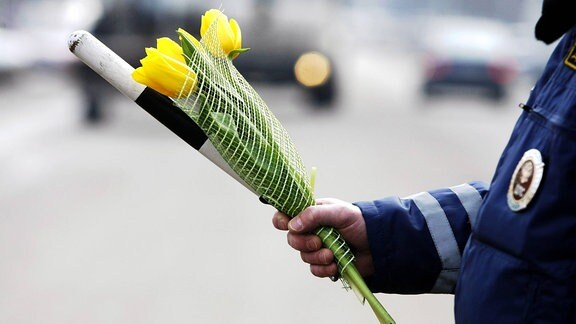 Polizist hält Verkehrsstab und Tulpen