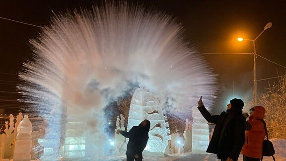 Neujahrstradition in Sibirien: Heißes Wasser wird aus einer Tasse nach oben geworfen und rieselt gefroren auf den Boden zurück