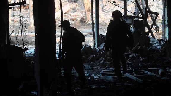 Russische Soldaten laufen durch ein zerstörtes Gebäude