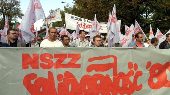 Mitglieder der Gewerkschaft Solidarnosc '80 tragen das Transparent der Gewerkschaft, während sich am Freitag, den 24. September 1999 in Warschau rund 20.000 Bauern und Gewerkschaftsmitglieder zu einer Kundgebung gegen die Wirtschaftsreformen der Mitte-Rechts-Regierung von Premierminister Jerzy Buzek versammeln.