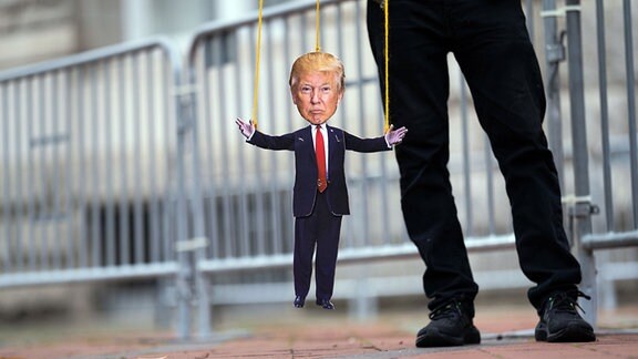 Ein Mann hält eine Donald Trump Marionette