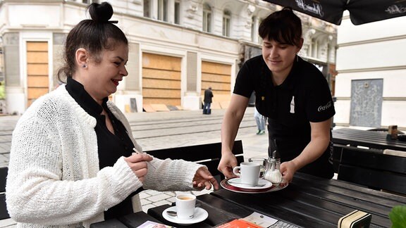 Kellnerin bringt einer Frau Kaffee
