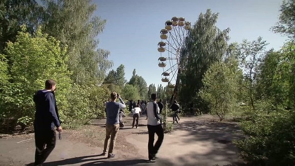 Menschen fotografieren ein gelbes Riesenrad
