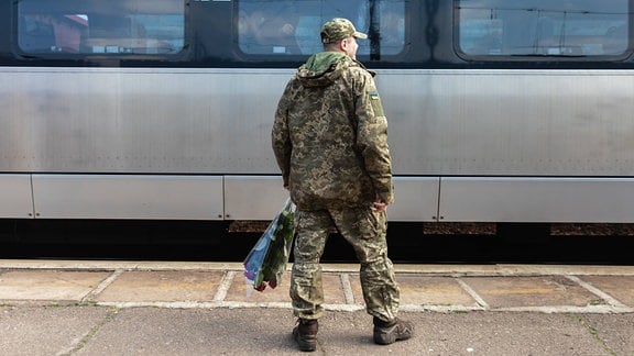Ein Soldat auf einem Bahnsteig vor einem Zug