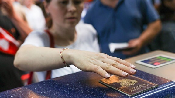 Eine Frau legt einen Reisepass auf einen Tisch.