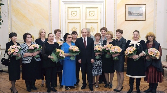 Russlands Präsident Wladimir Putin (Mitte) und Frauen posieren für ein Gruppenfoto während einer Teeparty im Moskauer Kreml am Internationalen Frauentag am 8. März. 