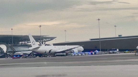 Eine Flugzeug auf einer Flughafen umgeben von vielen Rettungsfahrzeugen