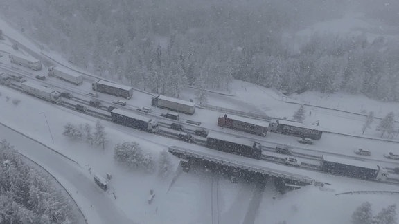 Stehende Lastkraftwagen von oben: Wegen starkem Schnee ist kein Weiterfahren möglich.