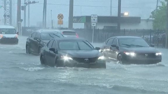 Autos fahren durch Wasser auf einer überfluteten Straße