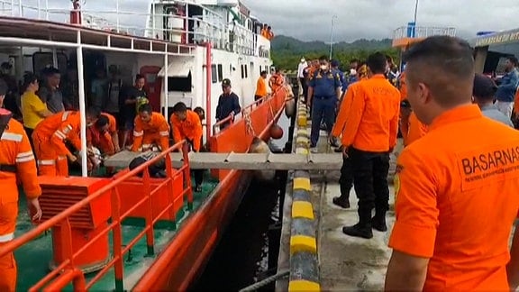 Eine Boot am Steg, Zivilisten und Helfern in Uniform 
