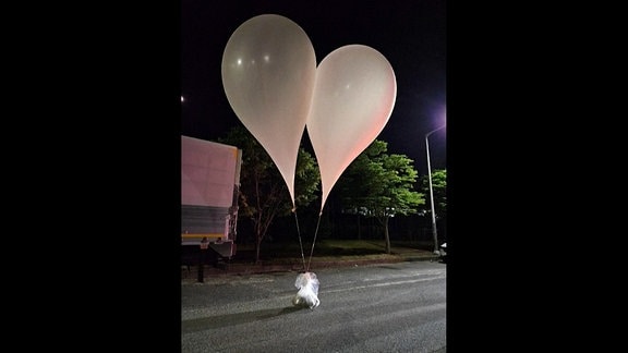Nacht: Zwei Ballons , an denen eine Tüte hängt