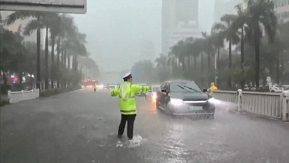Ein Verkehrspolizist leitet Stadtverkehr im Wasser stehend. 