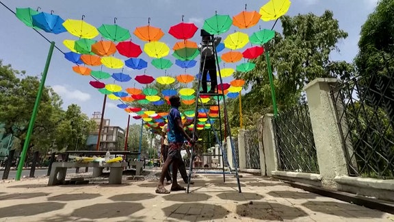 Bunte Regenschirme, die über einem Platz aufgehängt werden. 