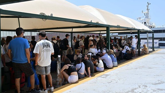 Reisende warten am Hafen von Neapel in einer Schlange vor den Ticketschaltern nach Capri.