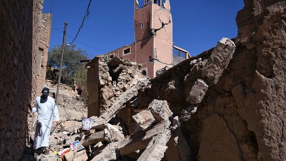 Ein Mann geht durch die Trümmer vor einer beschädigten Moschee. 