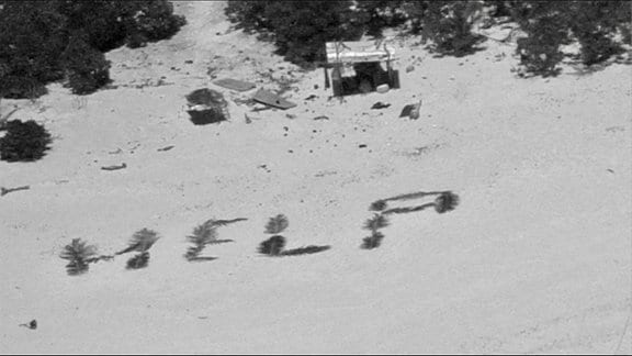 An einem Strand auf der Insel Pikelot ist die Botschaft «Help» mit Palmwedeln geschrieben. 