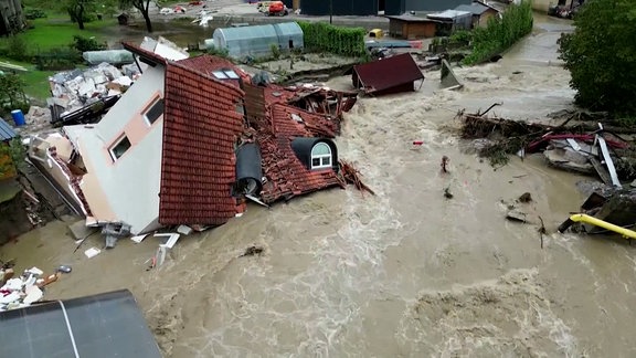 Ein zerstörtes Haus von Wassermassen umgeben