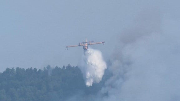 Ein Löschflugzeug über einem brennenden Wald in Spanien 