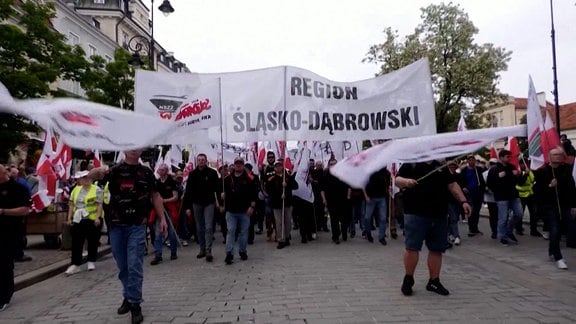 Demonstranten tragen ein großes Banner in polnischer Sprache.