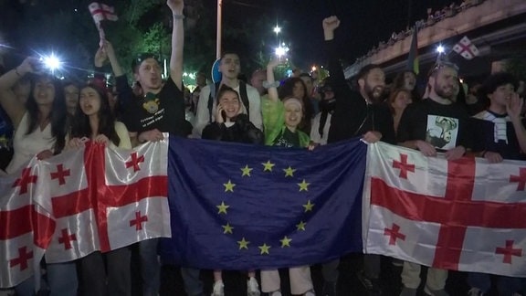 Junge Menschen schwenken EU-Fahne und georgische Flaggen