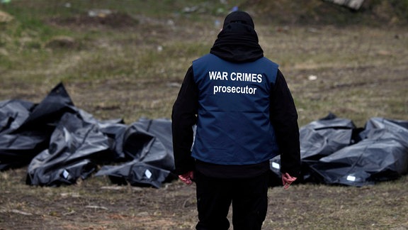 Ein Ermittler eines internationalen Forensik-Teams trägt 2022 eine Weste mit der Aufschrift "War Crimes Prosecutor".