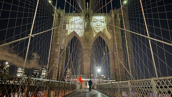 Während einer -Gedenk-Zeremonie wurden Bilder von New Yorkern, die durch die Pandemie verloren gegangen waren, auf die Brooklyn Bridge projiziert.