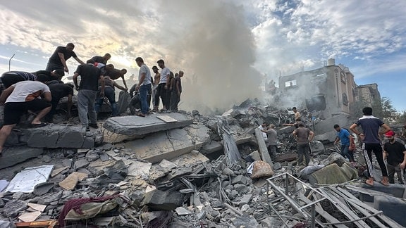 Palästinenser suchen nach einem israelischen Luftangriff im Flüchtlingslager Nuseirat im Gazastreifen zwischen den Trümmern eingestürzter Gebäude nach Überlebenden.