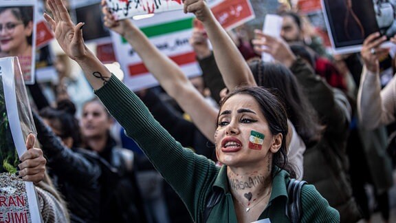 Eine Demonstrantin, die die Farben der iranischen Flagge auf der Wange geschminkt hat, ruft Slogans, während einer Demonstration gegen das Regime im Iran