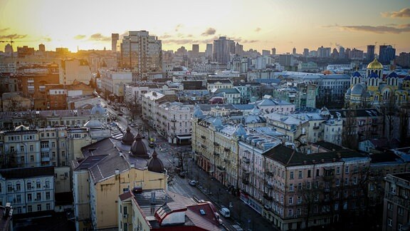 Die Sonne geht hinter den Häusern der ukrainischen Hauptstadt Kiew auf.