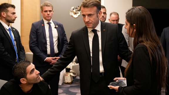 Emmanuel Macron (M), Präsident von Frankreich, trifft sich mit israelisch-französischen Staatsangehörigen, die Angehörige verloren haben, sowie mit Familien von Geiseln auf dem Ben-Gurion-Flughafen. 