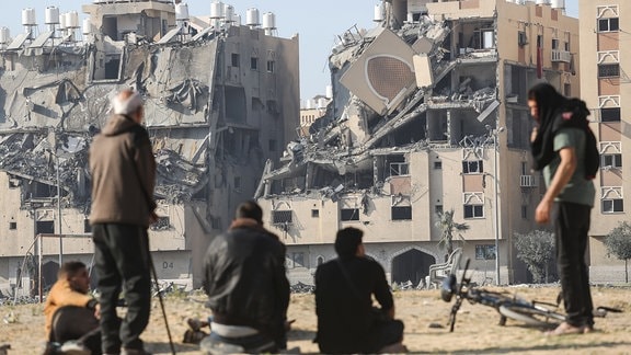Bewohner des von Katar finanzierten Wohnkomplexes Hamad Town im südlichen Gazastreifen sitzen nach einem israelischen Angriff vor den zerstörten Häusern.