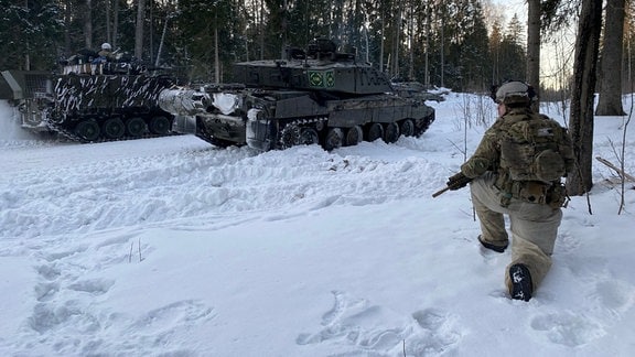 Ein Soldat kniet im Schnee im Wald neben einem britischen Kampfpanzer vom Typ Challenger 2 (vorne). Bei einer Winterübung in Estland trainieren Nato-Truppen Kampfeinsätze unter winterlichen Kältebedingungen. Beteiligt an der 1. von 15. Februar bis laufenden Ãbung sind auch Streitkräfte aus Frankreich und Großbritannien.