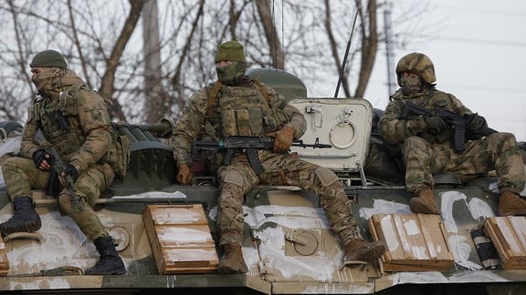 Russische Soldaten fahren 2022 auf einem gepanzerten Fahrzeug auf einer Straße nahe der Grenze zwischen Russland und der Ukraine mit.