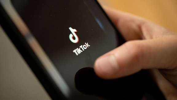 Ein Teenager tippt auf das TikTok-Logo auf einem Smartphone