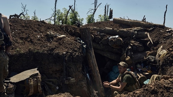 Ein ukrainischer Soldat sitzt in einem kürzlich eroberten russischen Graben an der Frontlinie in der Nähe von Bachmut.