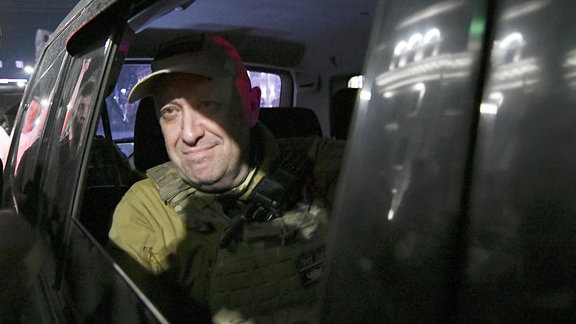 Mann in Militärkleidung schaut aus dem geöffneten Fenster eines schwarzen Autos