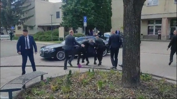 Fico wird von Sicherheitspersonal schwer verletzt zu seinem Auto gehieft. 